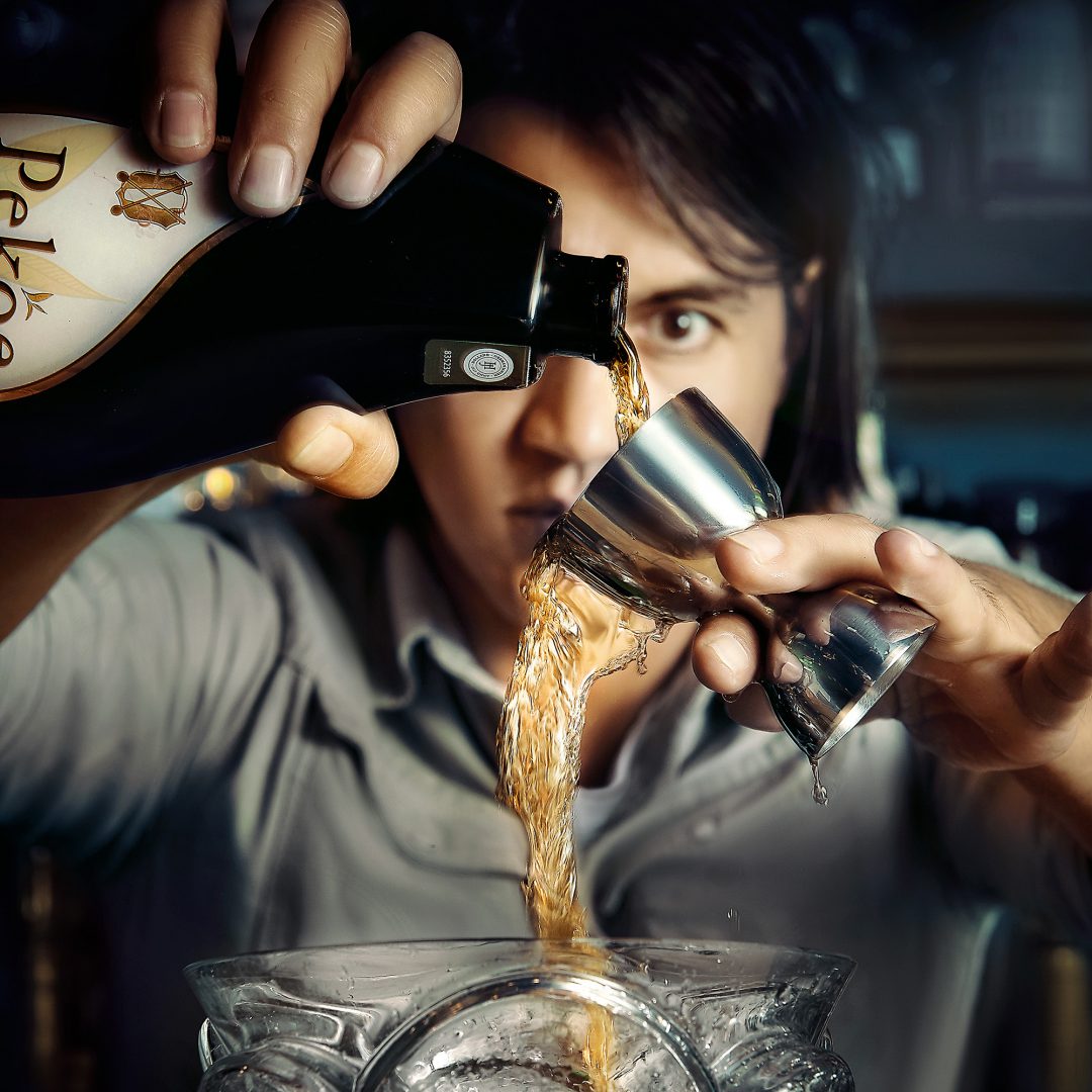 Zakelijke drankenfotografie van bartender die drank afmeet met jigger – professioneel beeld uit Den Haag