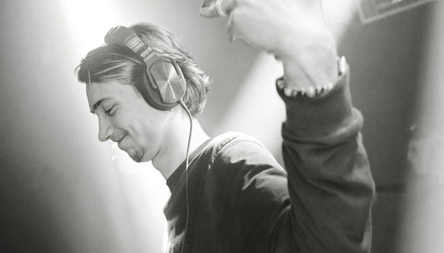 DJ met koptelefoon en hand omhoog tijdens techno set – documentaire festival fotografie in zwart-wit