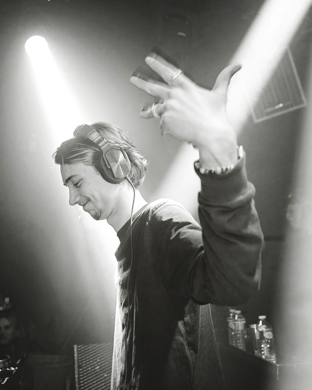 DJ met koptelefoon en hand omhoog tijdens techno set – documentaire festival fotografie in zwart-wit